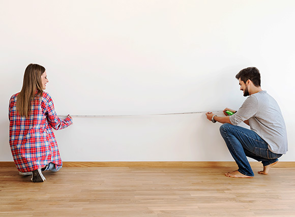 Couple measuring a room for furniture 